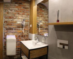 een badkamer met een wastafel en een bakstenen muur bij Pokoje Wieliczka in Wieliczka