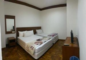 a bedroom with two beds and a television in it at EE HOTEL Johor Jaya in Johor Bahru