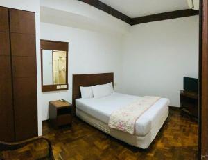 een slaapkamer met een wit bed en een spiegel bij EE HOTEL Johor Jaya in Johor Bahru