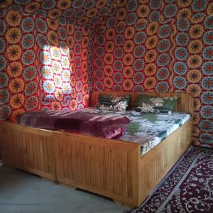 Cama de madera en habitación con ventana en Snow View Himalayan Adventure, en Kasol