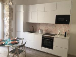 une cuisine avec des placards blancs et une table avec une salle à manger dans l'établissement La Terrazza sul mare - Dimora di Charme, à Giovinazzo