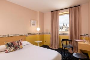 a hotel room with a bed and a desk and a window at LHotel - face au château - boutique hôtel et séminaires in Nantes