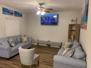a living room with two couches and a ceiling fan at D's Mississippi Vacation Home with Game room in Gulfport