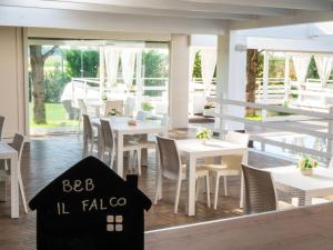 a restaurant with white tables and chairs and windows at B&B Il Falco in Castel del Monte
