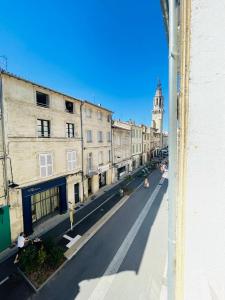 - Vistas a una calle de la ciudad con una torre del reloj en Charmant T2, Centre Historique, Place des Carmes en Aviñón