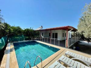 een zwembad met stoelen en een huis bij Avci Villa-Fethiye 3+1 in Garden with Private Pool, 10 minutes to the beach in Fethiye