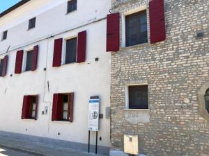 um edifício de tijolos com janelas vermelhas e um parquímetro em Palazzo Strassoldo bed & breakfast em Teòr