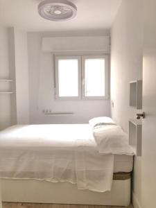 ein weißes Schlafzimmer mit einem Bett und einem Fenster in der Unterkunft FLEMING CENTRO in Granada