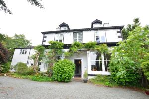 a white house with plants on the front of it at Beech Apartment in Bowness-on-Windermere