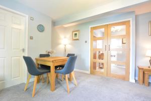 a dining room with a wooden table and blue chairs at Beech Apartment in Bowness-on-Windermere