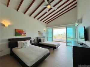 um quarto com 2 camas e uma televisão de ecrã plano em Casa Arcoíris: Espectacular casa en Cartagena con Acceso directo a la Playa em Cartagena das Índias