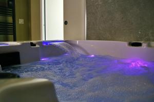 El baño incluye bañera con luces moradas y moradas. en Appartement luxueux avec Jacuzzi privatif en Roanne