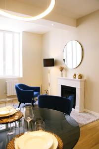 een woonkamer met een tafel en stoelen en een spiegel bij Appartement luxueux avec Jacuzzi privatif in Roanne