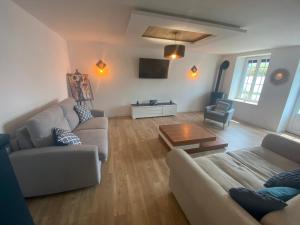ein Wohnzimmer mit einem Sofa und einem Tisch in der Unterkunft Belle maison avec grand jardin proche St Malo in Miniac-Morvan