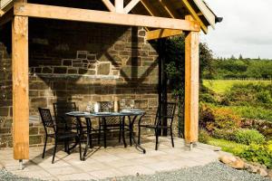 een patio met een tafel en stoelen onder een houten pergola bij Culdoach in Castle Douglas