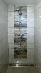 y baño con ducha y pared de madera. en GreenRiver Apartment, en Spodnje Gorje