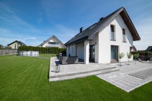 a white house with a green lawn at Dom Marina Mosty, Sauna Hot Tub Holiday Home near Rewa Gdańsk in Mosty