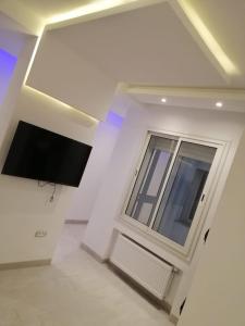 um quarto branco com uma televisão e uma janela em Derby de Cité el Khadra em Tunes