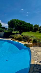 - une piscine bleue à côté d'un parcours de golf dans l'établissement SUPERBE VILLA-DOMAINE AVEC GOLF PISCINE ET TENNIS, à Saint-Cyr-sur-Mer