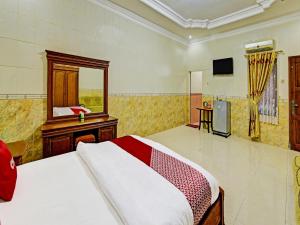 a bedroom with a bed and a mirror and a television at Collection O 91489 Hotel Tanjung Permata in Cilacap
