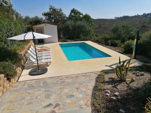 einen Pool mit einem Stuhl und einem Sonnenschirm in der Unterkunft Casa das Estevas in Alvaiade