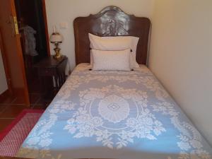 a bed with a blue and white comforter on it at Casa da Praça in Castelo Novo