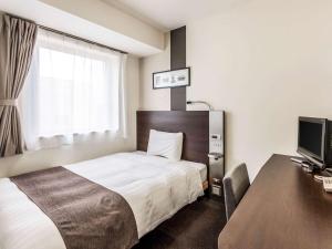 東京にあるコンフォートホテル東京神田のベッドとデスクが備わるホテルルームです。