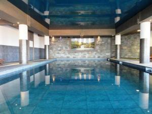a large swimming pool with blue water in a building at Arc 1800 Alpage du chantel Iseran SKI-in SKI-out in Arc 1800