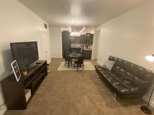 a living room with a black leather couch and a table at 2 CONDOS next to each other Perfect for GROUPS in Logan