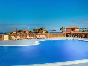 a large blue swimming pool with chairs and umbrellas at Villa Maracuya in Lajares
