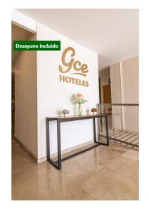 una mesa frente a una pared con un cartel de hoteles ce en Gce Hoteles en Cártama