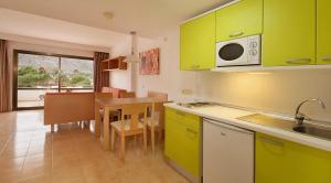 a kitchen with green cabinets and a table with a microwave at Sol de Alcudia Apartamentos in Port d'Alcudia