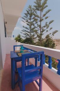a blue table and chair on a balcony with a tree at Auberge du Marabout in Sidi Kaouki