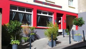 a red building with potted plants in front of it at Hôtel Le Cambronne in Nantes