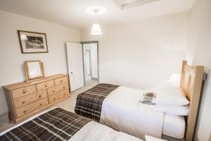 a bedroom with two beds and a dresser at Diamonds Laggan in Castle Douglas