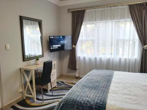 a bedroom with a bed and a desk and a television at Menlyn Mews BnB in Pretoria