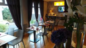 a dining room with tables and chairs in a restaurant at Hôtel Le Cambronne in Nantes