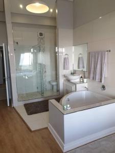 a bathroom with a tub and a shower and a sink at Beachfront 3-bedroom with Robben Island views in Cape Town