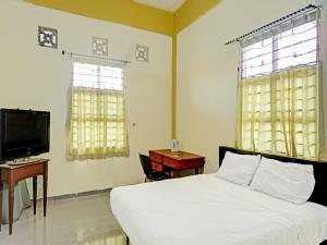 1 dormitorio con 1 cama, TV y escritorio en Collection O 91499 John Lebron House, en Sagulung