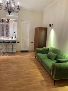 a living room with a green couch and a kitchen at Apartment Kostava 10 in Batumi