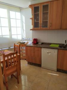 a kitchen with wooden cabinets and a table and chairs at APARTAMENTO BEATRIZ in A Pobra do Caramiñal