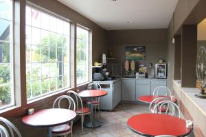 a restaurant with red tables and chairs and windows at University Inn and Suites Eugene in Eugene