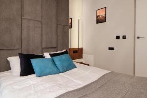 a bed with two blue pillows on top of it at Apartamenty Olimpijska by RENT4YOU in Olsztyn