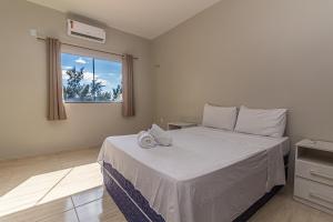 a bedroom with a bed with white sheets and a window at Praieiro pousada in Prea