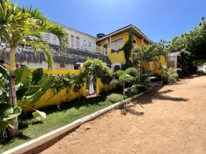 una casa amarilla con palmeras delante en Pousada Duna Beach, en Jericoacoara