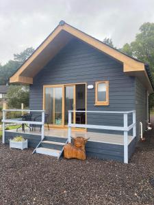 une maison bleue avec une vache assise à l'extérieur dans l'établissement Ben Nevis Manor Lodge & Indoor Private Hot-Tub, à Fort William