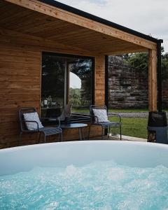 a hot tub in front of a house with chairs at Off the Track Getaway, Luxury Lodge in Crail