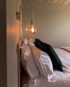 a bed with four pillows and two lights on it at Off the Track Getaway, Luxury Lodge in Crail