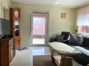 een woonkamer met een bank, een tafel en een klok bij Ferienhaus auf Usedom, Neeberg in Krummin