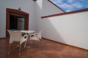 a patio with a table and chairs on a white wall at Hotel-Apartamento Carolina y Vanessa in San José